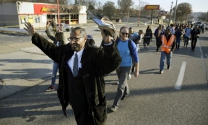  Marchers walk past a burned-out business in Ferguson, Missouri, on their way to Jefferson City. 